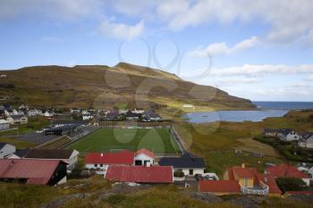 Scenic panoramic landscape of a picturesque village of Eidi with football stadium and traditional houses on the Faroe Islands