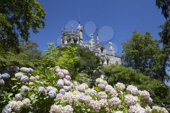 Quinta da Regaleira on a bright sunny day with blooming flowers in front.