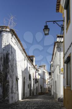 The view of narrow paved street of Evora with the cozy white houses. Evora. Alentejo. Portugal