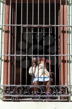 Havana, Cuba - 8 February 2015: Old lady looks from behind a barred window