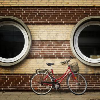Red bicycle on a wall with two round windows