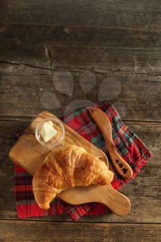 Fresh homemade croissant on a cutboard with butter and wooden knife