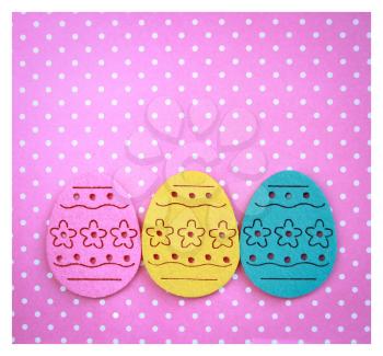 Decorated felt easter eggs yellow, blue and pink on a pinky polka dots background