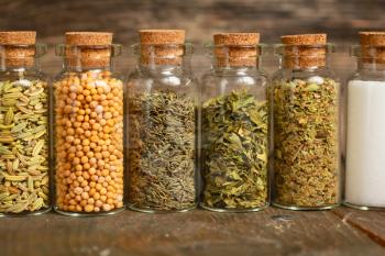 Spices, herbs and seeds in little jars in a row