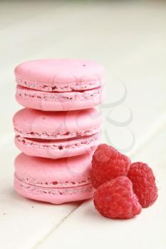 Pile of pink macaroons with fresh raspberry on a white table