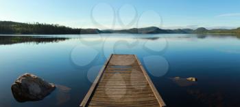 Wooden dock on a calm blue lake in Canada