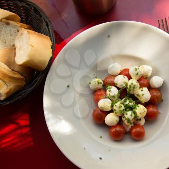 Top view of a delicious and fresh caprese salad, a tomato salad with bocconcini with fresh bread.