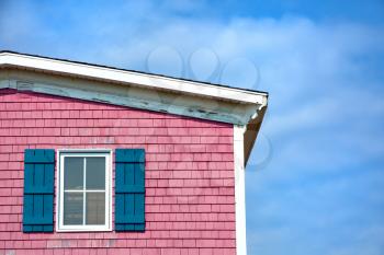 Architecture detail of a pink house with blue shuttered window against blue sky with space for your text