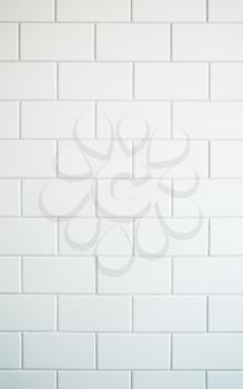 Vertical picture of a white mat tiles on a wall with grey cement