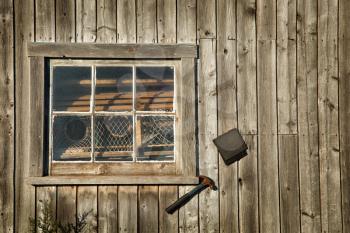 Wooden window on a grunge wooden wall with a rusty hammer