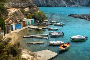 Fishing boats floating on turquoise water at Mandrakia in Milos Island in Cyclades in Greece
