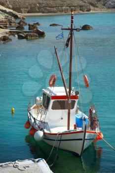 Fishing boat floating on turquoise water at Mandrakia in Milos Island in Cyclades in Greece
