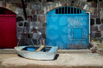 Pale blue boat on the jetty in Firopotamos village with his colourful houses in Milos in Greece