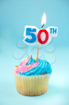 50th birthday cupcake with blue and pink icing on a blue background
