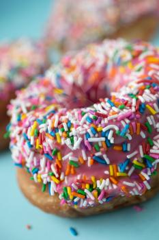 Donuts with pink icing and candies on a blue pastel background