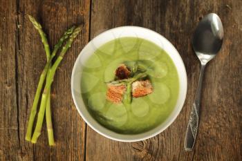 Top view of a asparagus soup in a white bowl on a rustic background
