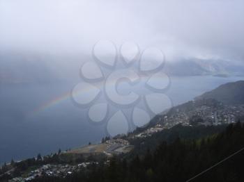 Royalty Free Photo of a Rainbow, a Mountain and Water