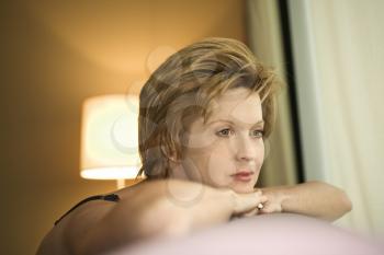 Royalty Free Photo of a Woman Draped Over a Sofa Looking Out the Window 
