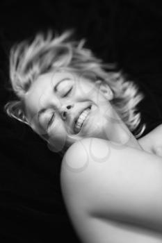 Royalty Free Photo of a Nude Woman Lying on Her Back Smiling With Eyes Closed