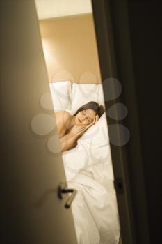 Royalty Free Photo of a View Through a Cracked Doorway of a Woman Sleeping in Bed