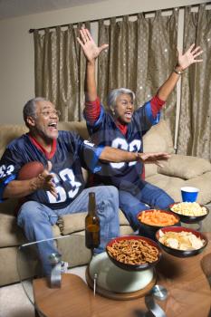Royalty Free Photo of a Couple Cheering and Watching a Football Game