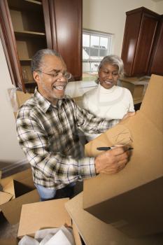 Royalty Free Photo of an Older Couple Labeling Moving Boxes in the Kitchen