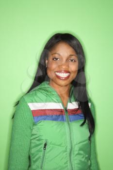 African-American mid-adult woman in green coat on green background.