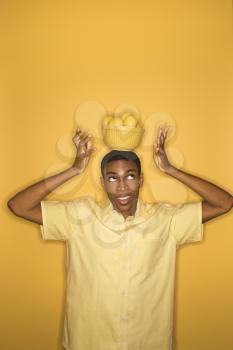 Royalty Free Photo of a Man Balancing a Bowl of Lemons on His Head