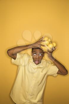 Royalty Free Photo of a Man Dropping a Bowl of Lemons He is Balancing on His Head