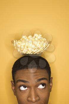 Royalty Free Photo of a Young Man Balancing a Bowl of Popcorn on His Head