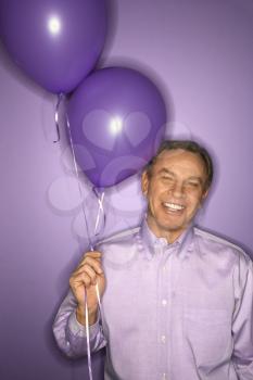 Royalty Free Photo of a Smiling Man on Holding Purple Balloons