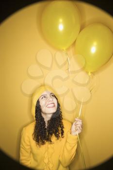 Royalty Free Photo of a Woman Holding Balloons Wearing a Yellow Raincoat on a Yellow Background