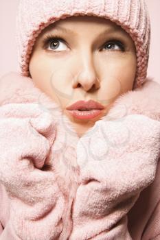 Caucasian mid-adult woman on pink background wearing winter coat and hat.