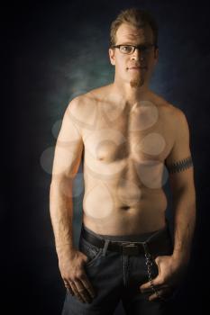 Portrait of shirtless adult Caucasian man on studio background looking at viewer.