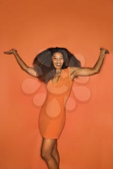 Royalty Free Photo of a Smiling Sexy African-American Woman With Big Hair on an Orange Background Wearing a Dress