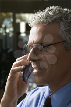 Close up profile of prime adult Caucasian man in suit talking on cellphone.