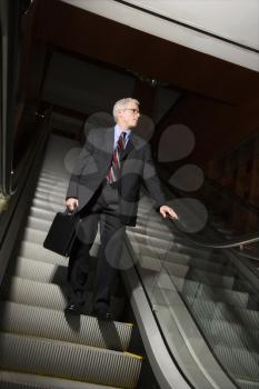 Royalty Free Photo of a Businessman on an Escalator Holding a Briefcase