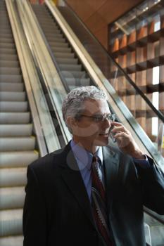 Royalty Free Photo of a Businessman Talking on a Cellphone on an Escalator 