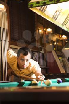 Royalty Free Photo of a Man Concentrating While Aiming at a Pool Ball While Playing Billiards