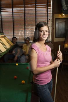 Portrait of woman standing by billiards table holding pool stick.