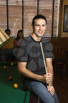Royalty Free Photo of a Man Leaning on a Billiards Table Holding a Pool Stick
