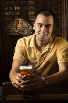 Royalty Free Photo of a Smiling Young Man Holding Beer in a Pub