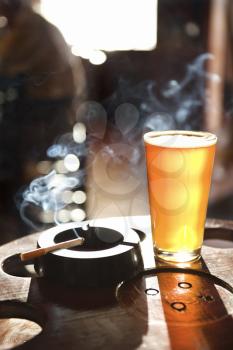 Royalty Free Photo of a Full Glass of Beer and Cigarette With Smoke Rising in a Nightclub