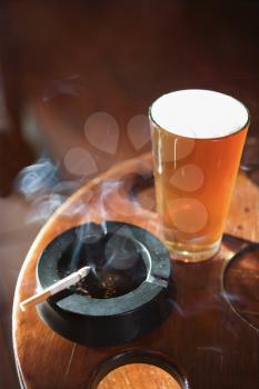 Royalty Free Photo of a Full Beer Glass and Cigarette With Smoke Rising in a Nightclub