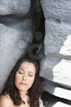 Royalty Free Photo of a Brunette Woman Leaning Against Boulders