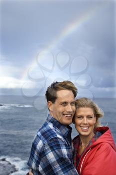 Royalty Free Photo of a Couple Standing by the Ocean With a Rainbow in the Background in Maui, Hawaii