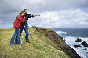 Royalty Free Photo of a Couple Looking Through a Camera From a Cliff Overlooking the Ocean in Maui, Hawaii
