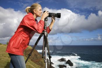 Royalty Free Photo of a Woman Holding a Camera on a Cliff Overlooking the Ocean in Maui, Hawaii
