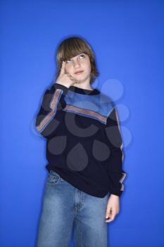 Royalty Free Photo of a Boy With One Hand Pointing at His Head Standing Against a Blue Background
