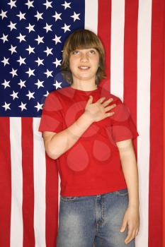Royalty Free Photo of a Boy With His Hand Over His Heart With an American Flag Background